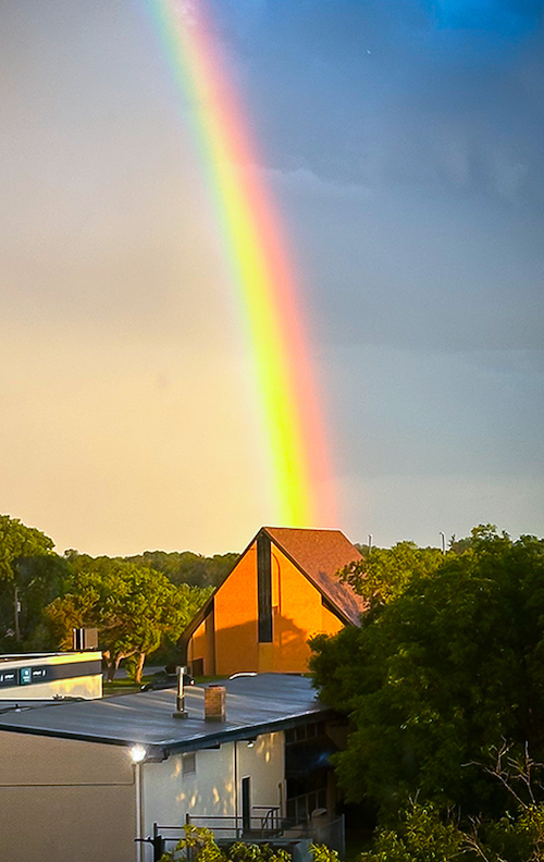 Photo of the church building with a rainbow landing on it